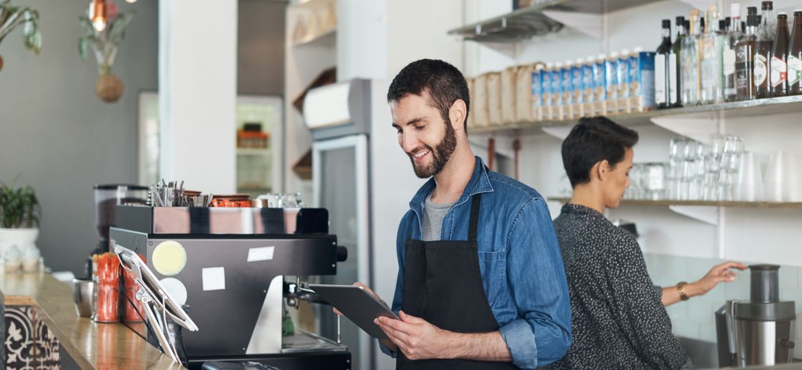 young man using a digital tablet in his coffee shop